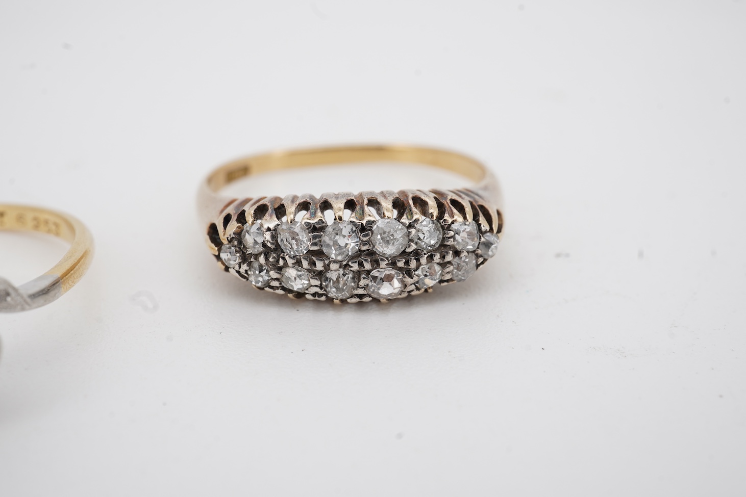 A mid 20th century 18ct, plat. and three stone diamond chip crossover ring, each stone in a heart shaped setting, size Q, together with an 18ct and fourteen stone diamond set two row ring, size P/Q, gross weight 6 grams.